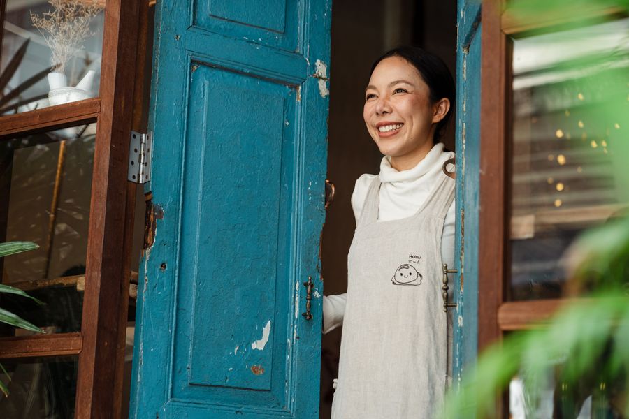 Café owner smiling at the door of her shop